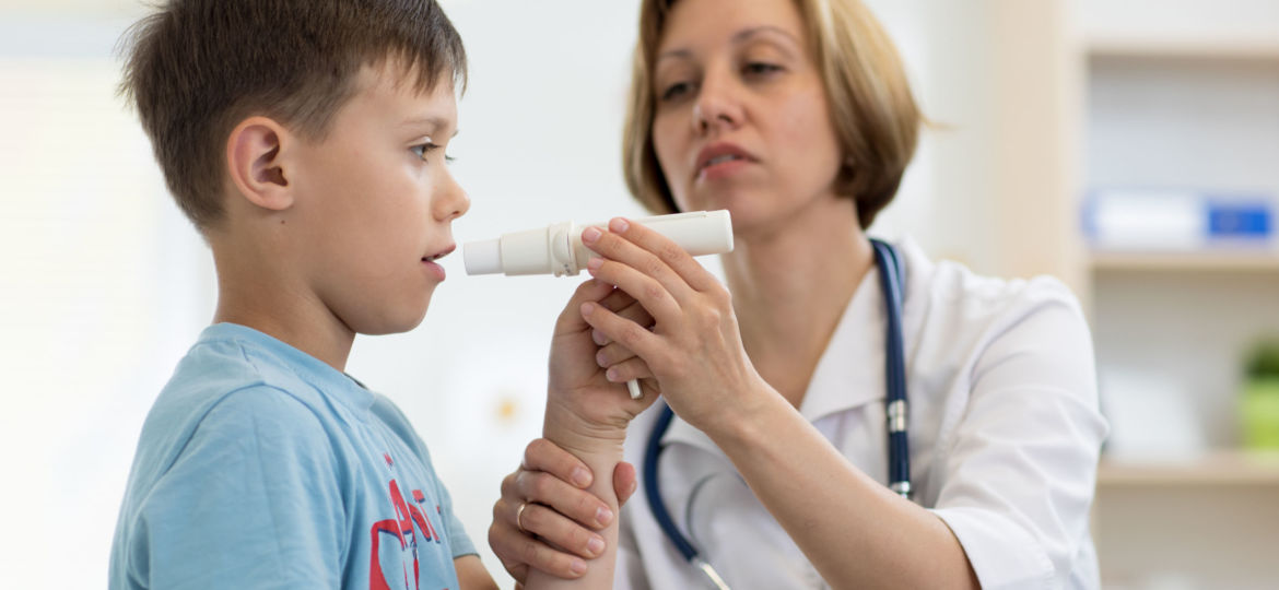 Little boy blowing to peak metr medical device. Doctor examining child's lungs
