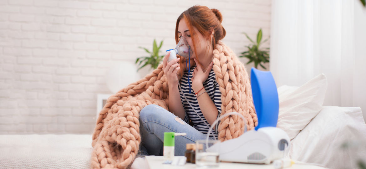 Young woman doing inhalation with a nebulizer at home